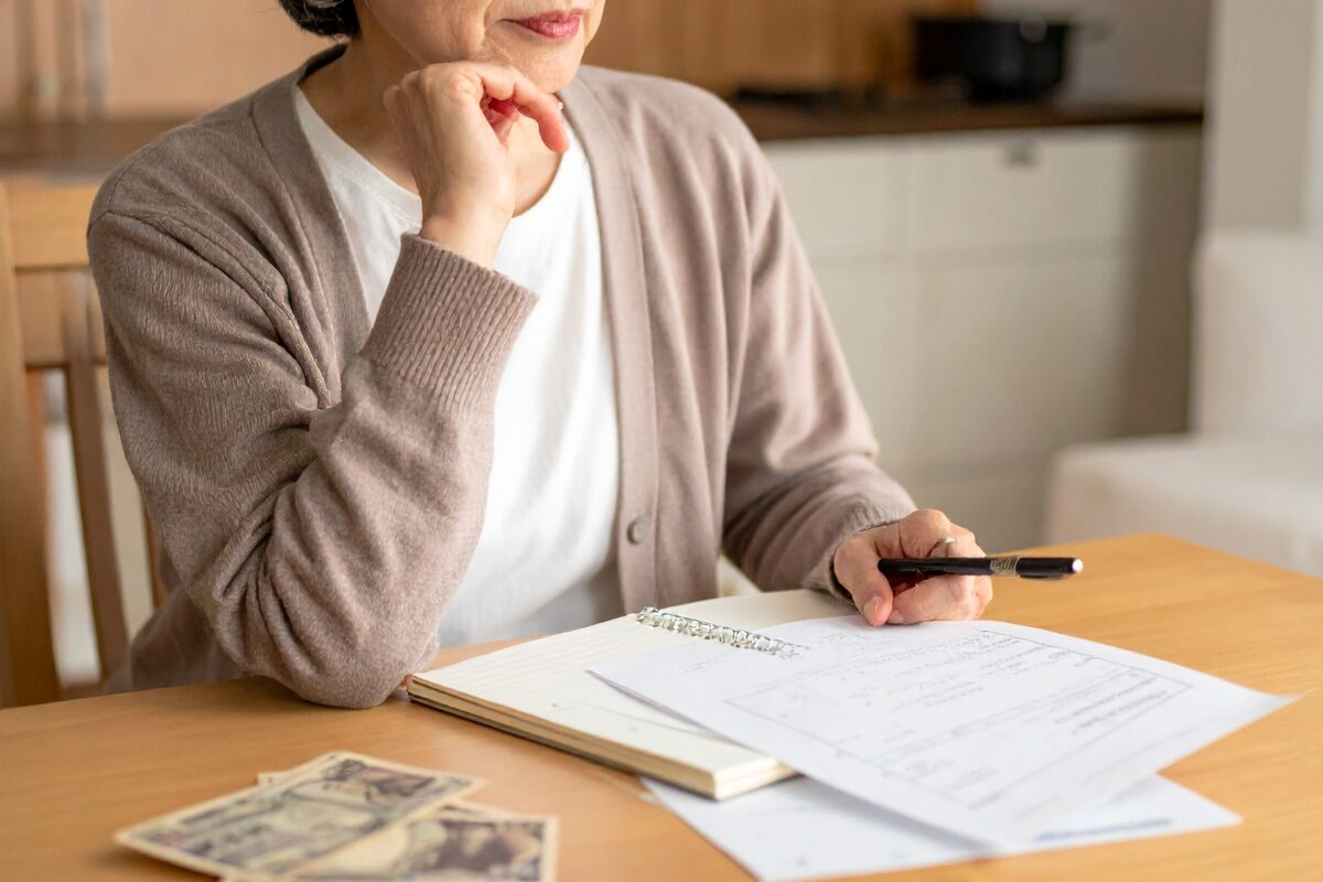 費用と予算が書いている書類をみて考え込んでいる女性。
