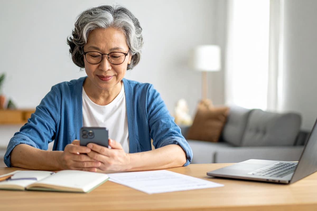 書類を前にスマートフォンで登記情報を確認する60代女性