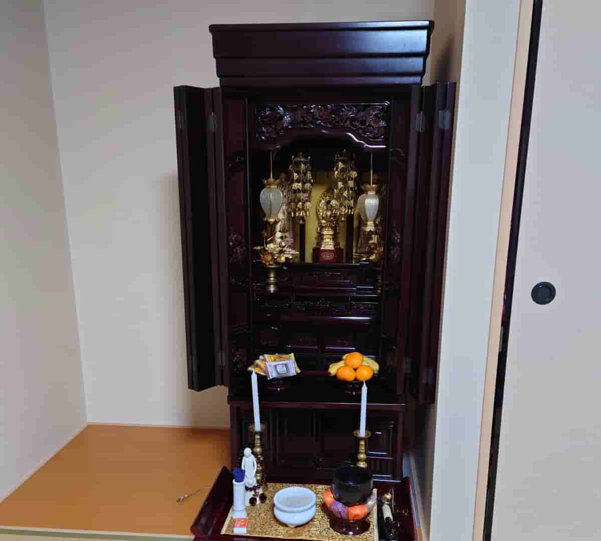 自宅の仏間に搬入したあとの仏壇。扉を開けた状態で、御本尊と脇掛、供え物が並んでいる